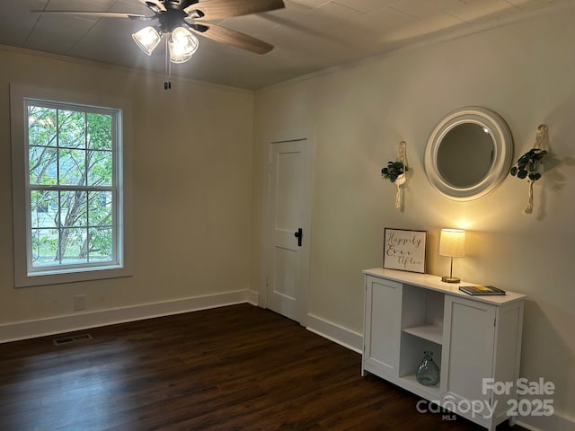unfurnished bedroom with ornamental molding, dark wood-style flooring, baseboards, and a ceiling fan