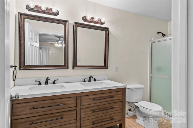 bathroom with tile patterned flooring, ceiling fan, vanity, a shower with shower door, and toilet