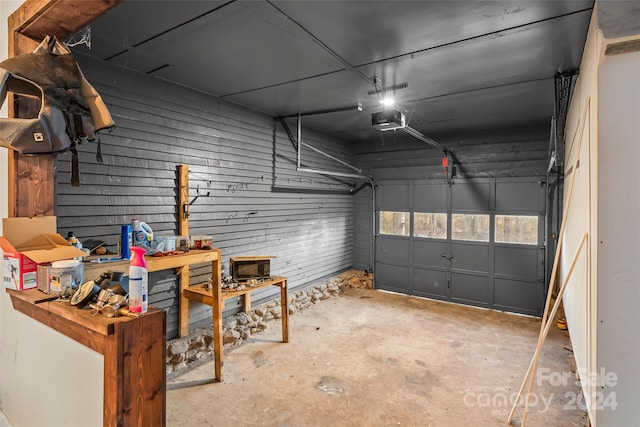 garage featuring a workshop area, wood walls, and a garage door opener