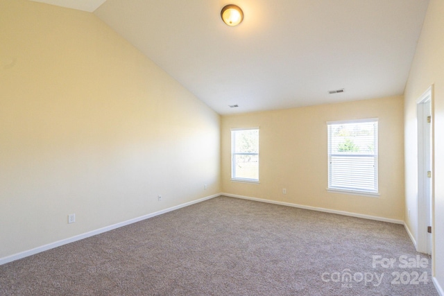 carpeted spare room with lofted ceiling