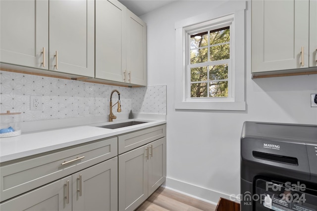 kitchen with gray cabinetry, light hardwood / wood-style floors, decorative backsplash, and sink