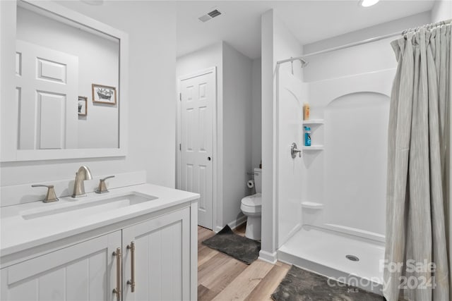 bathroom with toilet, a shower with curtain, vanity, and hardwood / wood-style flooring