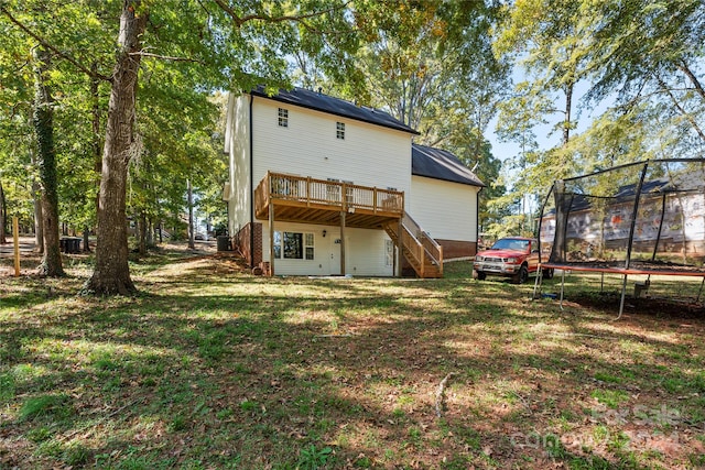 rear view of property featuring a yard, a trampoline, and a deck