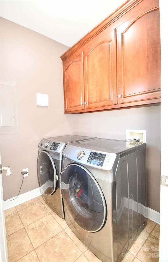 clothes washing area featuring cabinets, washer and clothes dryer, and light tile patterned floors