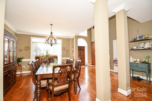 dining room featuring ornamental molding, decorative columns, a notable chandelier, and hardwood / wood-style flooring