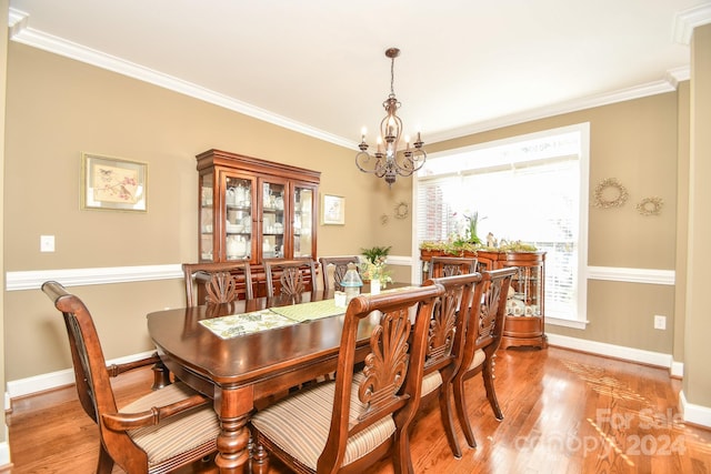 dining area featuring crown molding, a notable chandelier, and light wood-type flooring