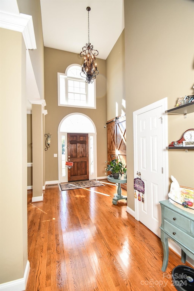 entryway with a notable chandelier, hardwood / wood-style flooring, and a high ceiling