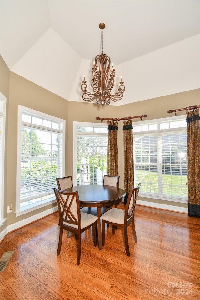 dining area with an inviting chandelier, light hardwood / wood-style flooring, and lofted ceiling