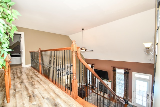 stairs with ceiling fan, lofted ceiling, and hardwood / wood-style floors