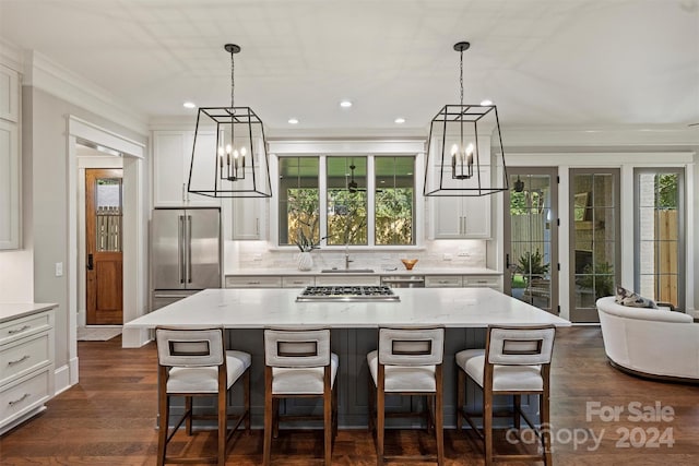 kitchen with light stone countertops, a kitchen island, decorative light fixtures, and appliances with stainless steel finishes