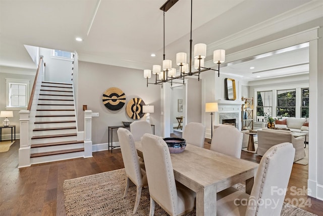 dining room with a notable chandelier, ornamental molding, dark wood-type flooring, and a high end fireplace