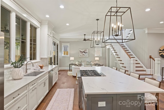 kitchen with white cabinets, a spacious island, sink, decorative backsplash, and appliances with stainless steel finishes