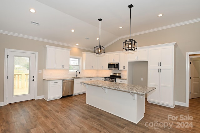 kitchen featuring a wealth of natural light, a kitchen island, stainless steel appliances, and lofted ceiling