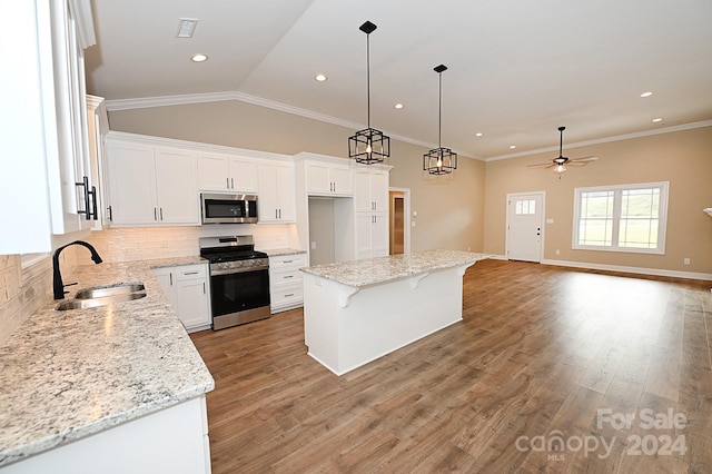 kitchen with appliances with stainless steel finishes, ceiling fan, sink, white cabinets, and a center island