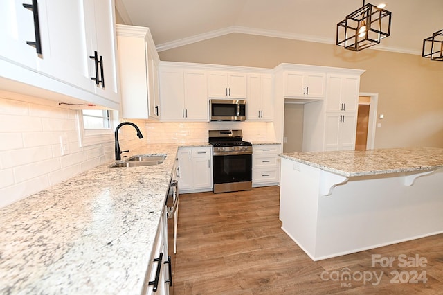 kitchen featuring a kitchen bar, appliances with stainless steel finishes, sink, pendant lighting, and white cabinetry