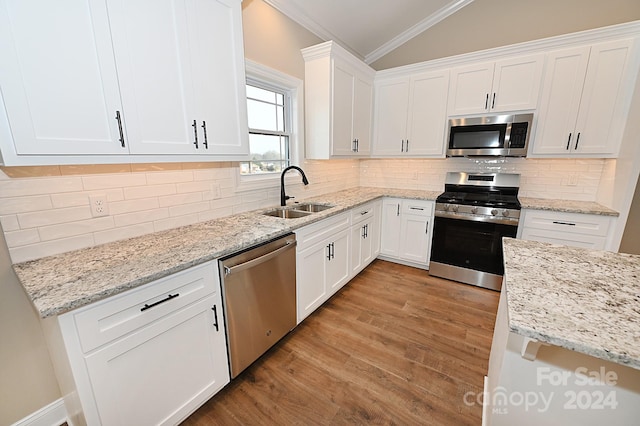 kitchen with lofted ceiling, sink, white cabinetry, and stainless steel appliances