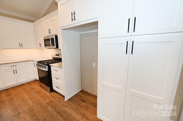 kitchen with light stone counters, white cabinetry, stainless steel appliances, and light wood-type flooring