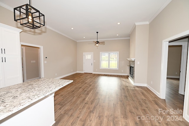 unfurnished living room with wood-type flooring, ceiling fan, and ornamental molding