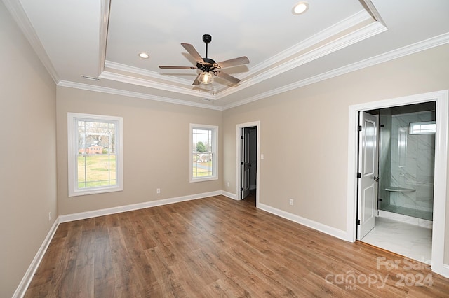 unfurnished bedroom with ensuite bathroom, a raised ceiling, ceiling fan, crown molding, and wood-type flooring