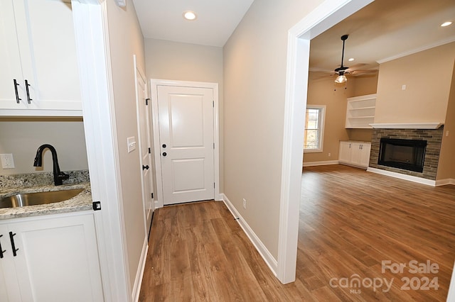 hall with light hardwood / wood-style floors, crown molding, and sink