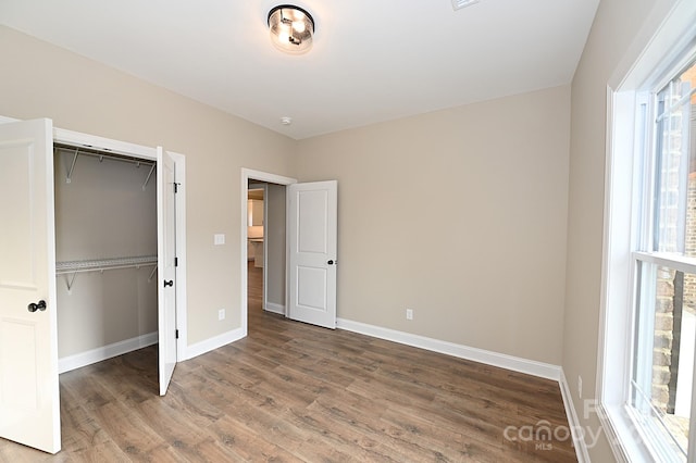 unfurnished bedroom featuring hardwood / wood-style floors, a closet, and multiple windows