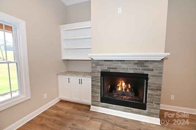 interior details featuring hardwood / wood-style flooring, ornamental molding, and a brick fireplace