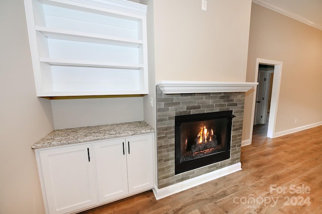 room details featuring crown molding, hardwood / wood-style floors, built in features, and a brick fireplace