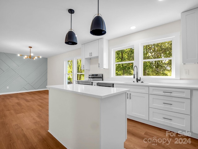 kitchen featuring white cabinetry, electric stove, pendant lighting, light hardwood / wood-style floors, and sink