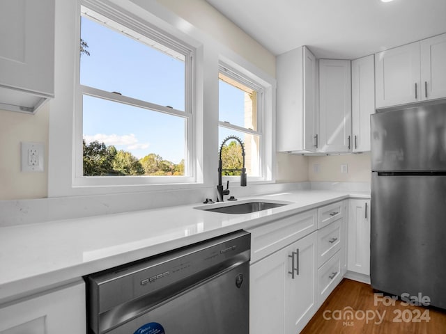 kitchen with appliances with stainless steel finishes, white cabinetry, sink, and plenty of natural light