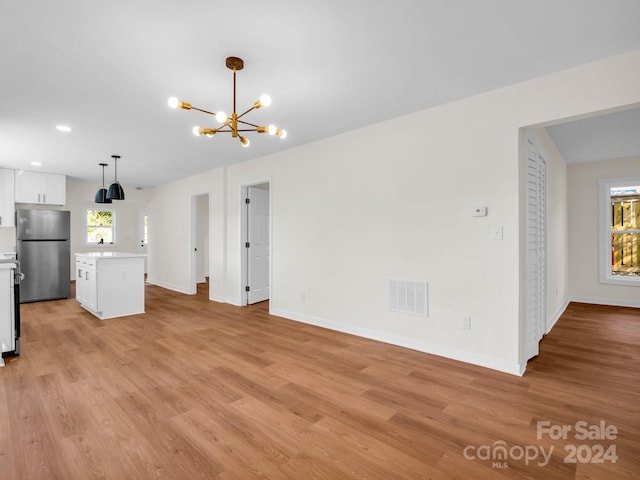 unfurnished living room featuring light hardwood / wood-style floors and a chandelier