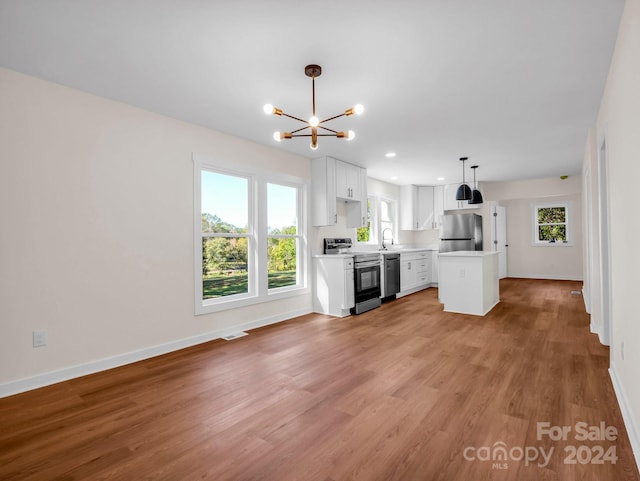 kitchen with a healthy amount of sunlight, a kitchen island, appliances with stainless steel finishes, and white cabinetry