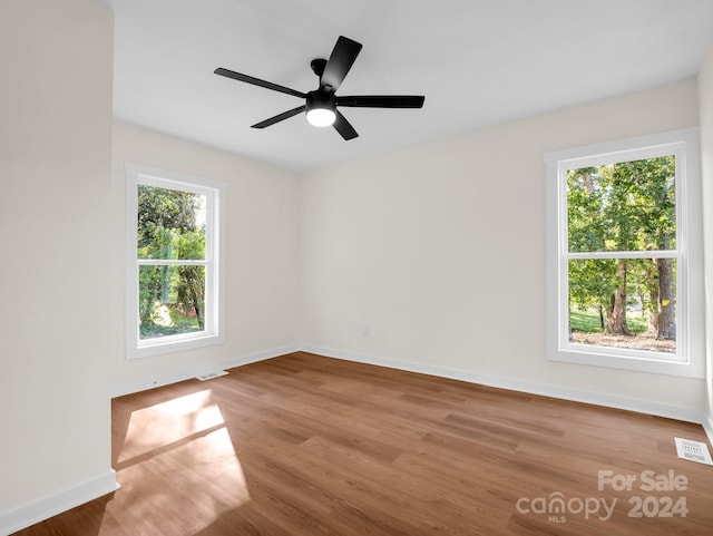 spare room with light hardwood / wood-style floors, a healthy amount of sunlight, and ceiling fan