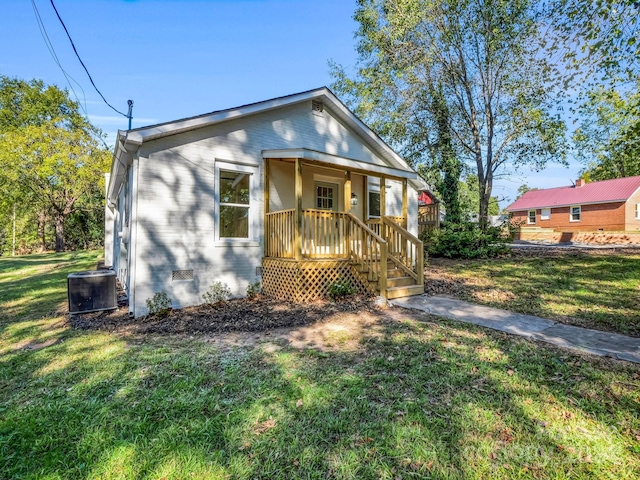 bungalow-style house with a front yard, cooling unit, and a porch