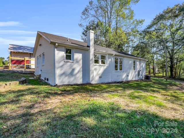 rear view of property featuring a yard and central air condition unit