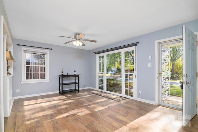 unfurnished living room with wood-type flooring, ceiling fan, and a healthy amount of sunlight