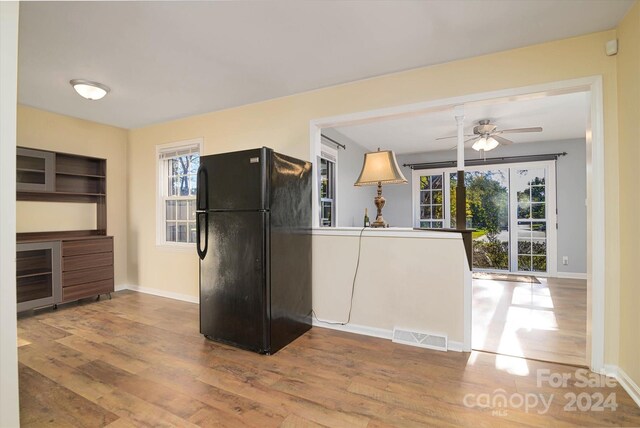 kitchen featuring ceiling fan, black refrigerator, light hardwood / wood-style floors, and plenty of natural light