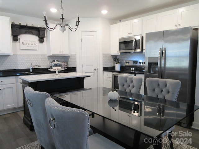 kitchen featuring a kitchen island, white cabinetry, stainless steel appliances, and backsplash