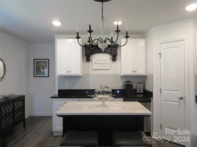 kitchen with dark hardwood / wood-style flooring, white cabinetry, decorative backsplash, a breakfast bar area, and an inviting chandelier