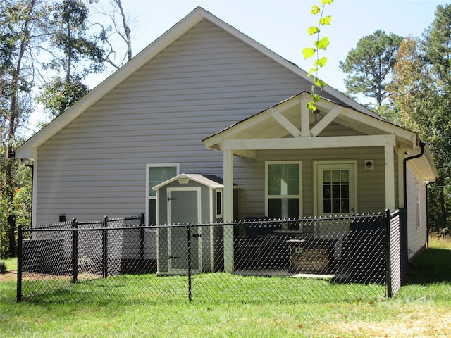 back of house with a porch, a storage unit, and a lawn