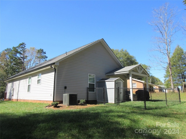 view of side of home with central AC and a yard