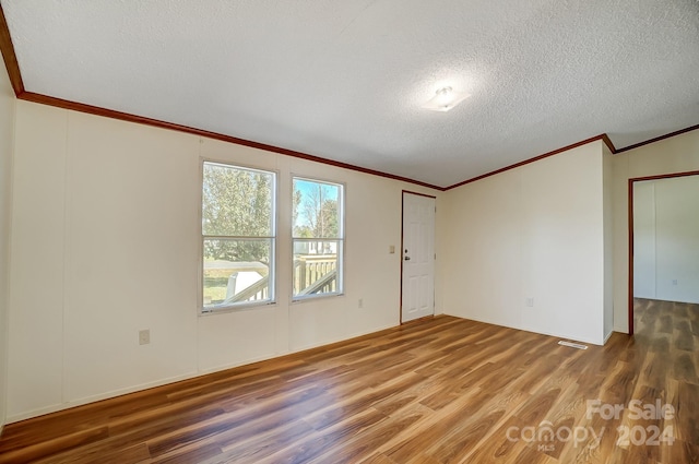 spare room with a textured ceiling, crown molding, and hardwood / wood-style flooring