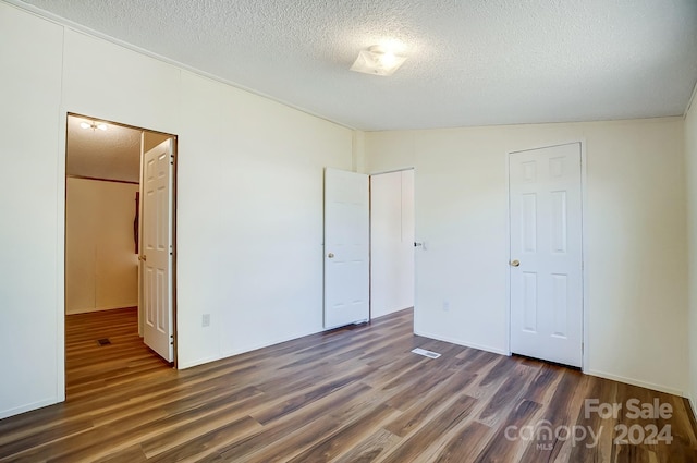 unfurnished bedroom with lofted ceiling, dark hardwood / wood-style floors, and a textured ceiling