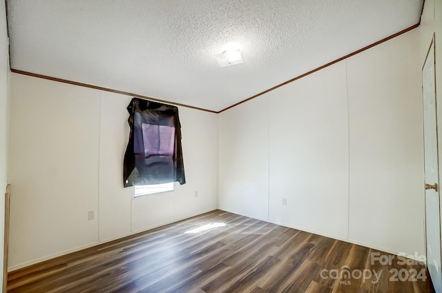 empty room with dark wood-type flooring, crown molding, and a textured ceiling