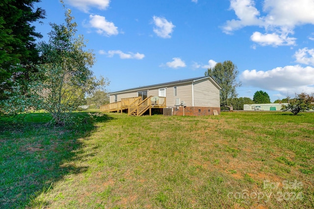 rear view of property featuring a yard, a deck, and central air condition unit