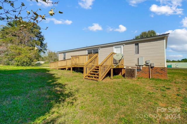 rear view of property with central AC, a deck, and a lawn