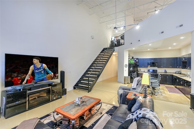 living room with sink, a fireplace, rail lighting, and a high ceiling