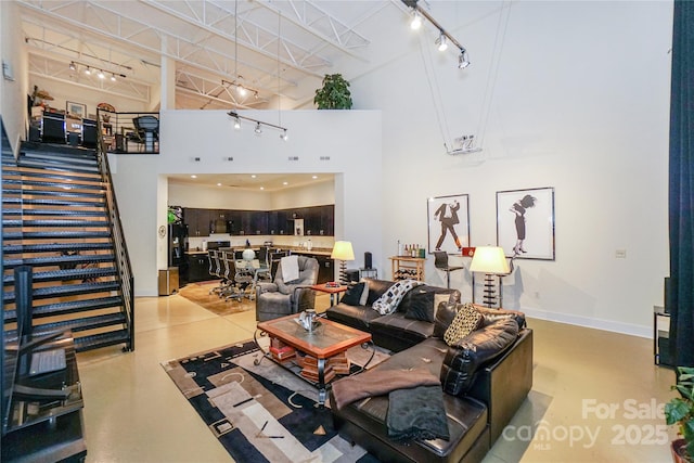 living room with a towering ceiling and rail lighting