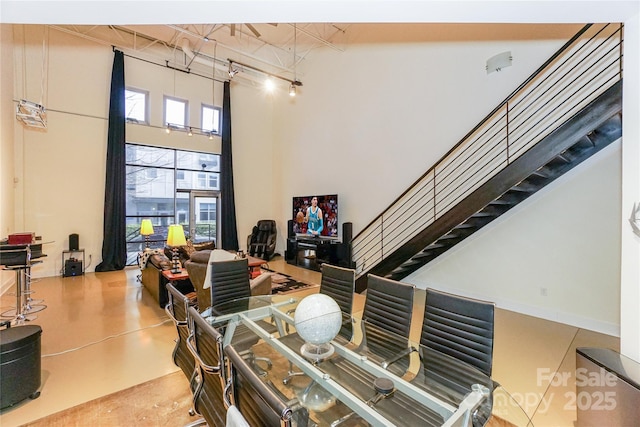 dining space featuring concrete floors and a high ceiling