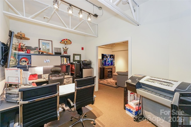 carpeted office featuring rail lighting and a towering ceiling