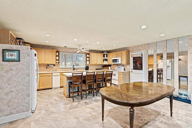 dining space featuring ceiling fan, a textured ceiling, sink, and light colored carpet